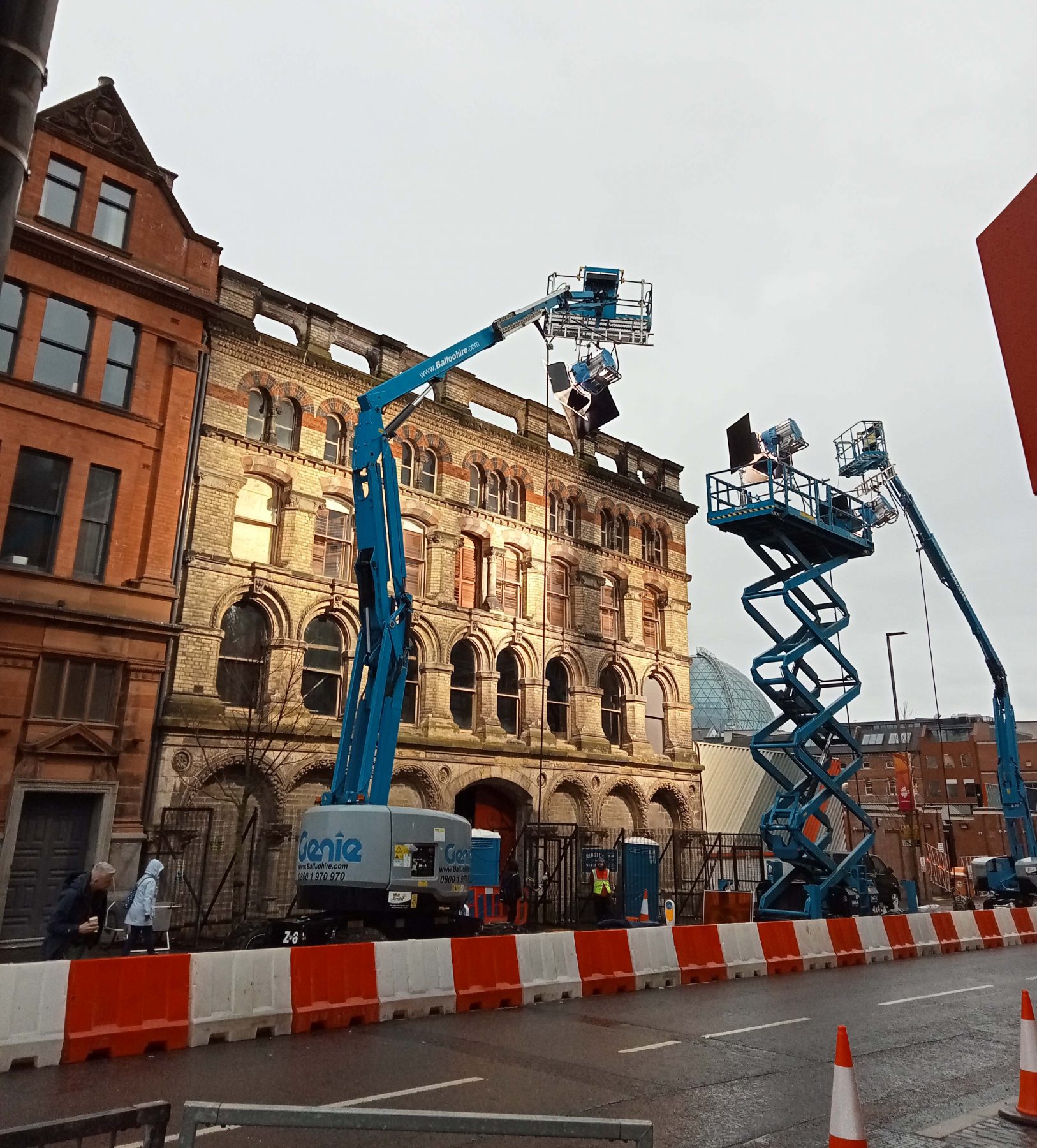 Large scissor lifts with lighting rigs directed onto a Victorian Brick Façade.