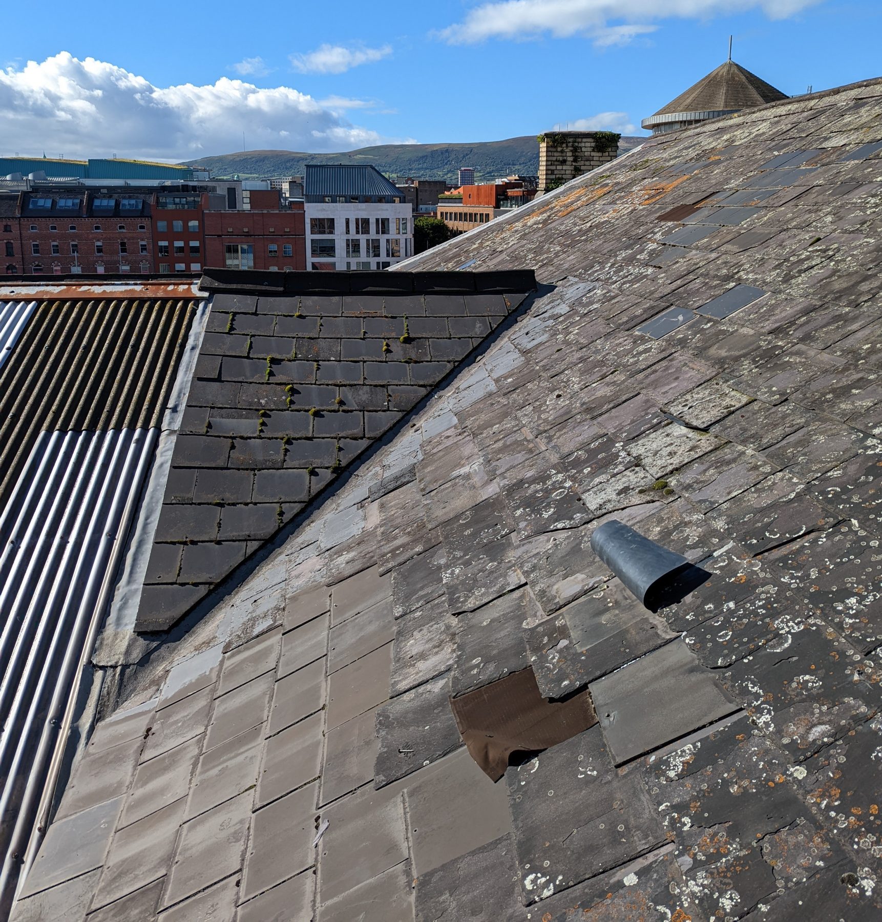 Slate roof in poor condition with patch repairs. 